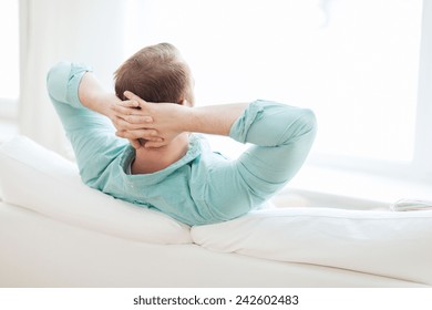 Home, Leisure, Relax And Happiness Concept - Man Lying Or Sitting On Sofa At Home From Back