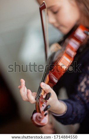 Home lesson for a girl playing the violin. The idea of activities for children during quarantine. Music concept. Selective focus