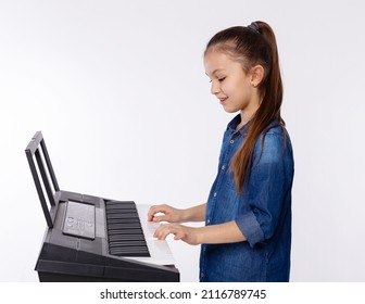 Home lesson of music. Cute girl learning to play piano keyboard synthesizer on white background. Studying the music at home