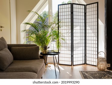 Home living room with wood and paper divider screen blocking sun from window, black metal accent table and sofa, natural colors. - Shutterstock ID 2019993290