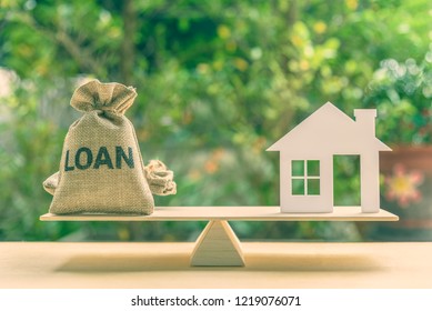 Home loan, reverse mortgage and saving for a real estate concept : House model, loan bag on basic balance scale, depicts saving for a house or flat manageable and turn a home buying dream into reality - Shutterstock ID 1219076071