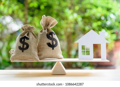 Home loan / reverse mortgage or transforming assets into cash concept : House paper model , US dollar hessian bags on a wood balance scale, depicts a homeowner or a borrower turns properties into cash - Shutterstock ID 1086642287