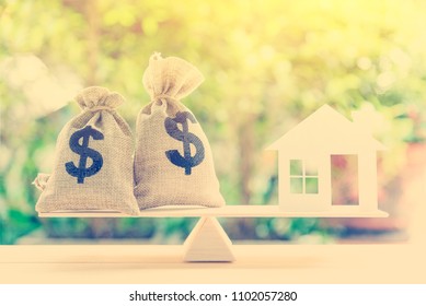 Home loan / reverse mortgage or transforming assets into cash concept : House paper model, US dollar hessian bags on a basic balance scale, depicts a homeowner or a borrower turns properties into cash