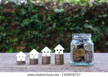 Home loan / Savings money for asset refinancing concept. Small house paper on stacks of coins. Depicts a homeowner or a borrower turns properties into cash, saving money to buy shelter.