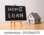 Home loan is written on small blackboard and house model on wooden table with white wall background. Home loan, mortgage loan, personal financial, buying home, banking and refinancing concept.