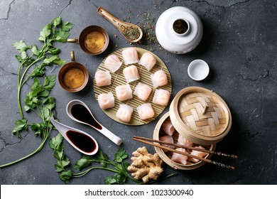 Home made chinese and korean dumplings served on the traditional steamer and bamboo mat decorated with soy sauce, parsley, giner and green tea. Top View