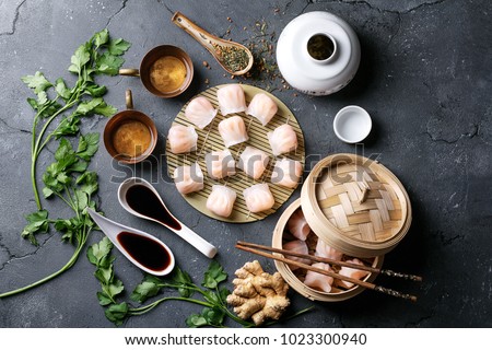 Home made chinese and korean dumplings served on the traditional steamer and bamboo mat decorated with soy sauce, parsley, giner and green tea. Top View