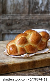 Home made fresh braided challah bread in white table cloth on wooden surface. Jewish bread for Shabat - vertical omage