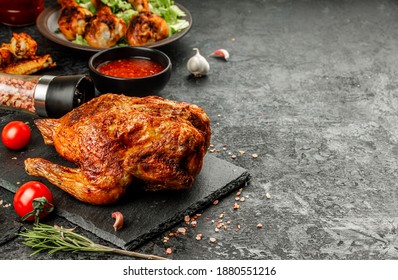 Home made grilled fried roast chicken with holden brown crust on black stone plate with tomato, rosemary and sauce - Shutterstock ID 1880551216