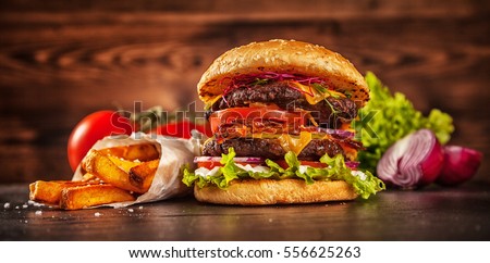Home made hamburger with lettuce, cheese, beef meat and french fries placed on old wooden table