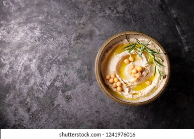 Home made hummus bowl, decorated with boiled chickpeas, herbs, pita and olive oil over a rustic metal background. Top View. - Shutterstock ID 1241976016