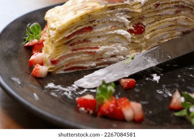 Home made mille crepe cake, a thin crepe layered with cream and topped with strawberries. - Shutterstock ID 2267084581