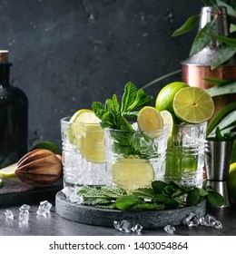 Home Made Mojito Cocktail Decorated With Lime, Lemon, Mint Leaves, Ice Cubes, Eucalyptus Tree And Copper Shaker Over Dark Background. Square Image