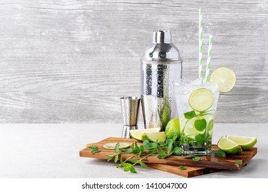 Home Made Mojito Cocktail Decorated With Lime, Mint Leaves, Ice Cubes And Silver Shaker Over White Bright Background