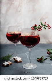 Home Made Mulled Wine Served In The Wine Glasses Decorated With Christmas Star Cookies, Red Berries, Pine Tree And Dry Oranges. 