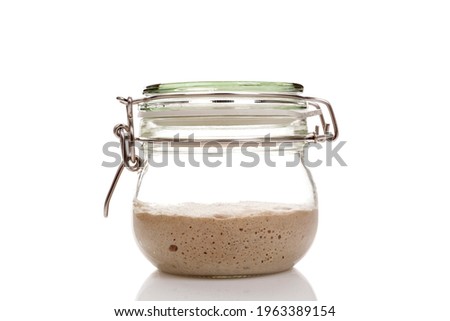 Home made starter yeast growing in a glass jar isolated on white background.