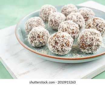 Home Made Vegan Energy Protein Balls With Coconut Flakes, Almond Butter, Oats, Nuts, Dates, Dried Fruit, Flax And Hemp Seeds Served On White Wooden Board.