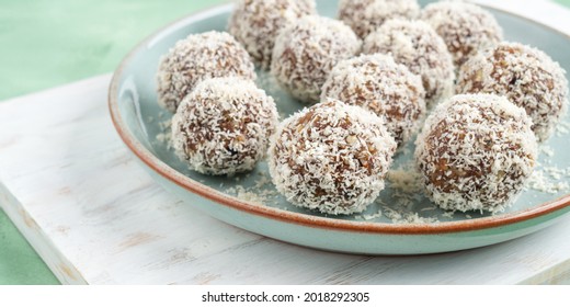 Home Made Vegan Energy Protein Balls With Coconut Flakes, Almond Butter, Oats, Nuts, Dates, Dried Fruit, Flax And Hemp Seeds Served On White Wooden Board.