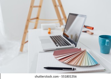 Home makeover, renovation and decoration: laptop on a desktop with color swatches and paint rollers - Powered by Shutterstock