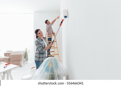 Home makeover and renovation: young happy couple painting their new house interiors using paint rollers