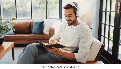 Hogar, hombre y sonrisa con auriculares para notebook, escribiendo pensamientos y reflexión personal con música. Sofá, persona masculina y felicidad con pista de audio para diario, diario o para hacer lista en la sala de estar