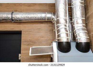 Home mechanical ventilation with heat recovery hanging on the wall, visible dirty filters sticking out of the device. - Shutterstock ID 2131129829