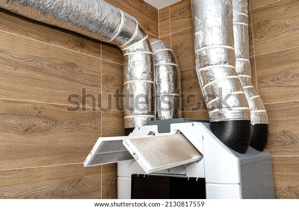 Home
mechanical ventilation with heat recovery hanging on the wall,
visible dirty filters sticking out of the
device.