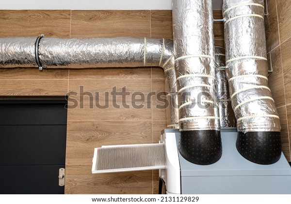 Home\
mechanical ventilation with heat recovery hanging on the wall,\
visible dirty filters sticking out of the\
device.