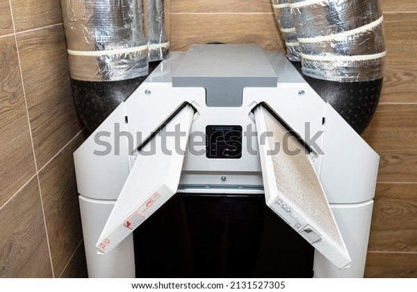 Home mechanical ventilation with heat recovery\
hanging on the wall, visible dirty G4 filter and clean F7 filter\
sticking out of the\
machine.