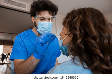 Home medical visit during Coronavirus Pandemic. Healthcare worker with protective equipment, performs nasal swab for Covid-19 Antigen test, PCR test, to a female patient at home or clinic. - Powered by Shutterstock