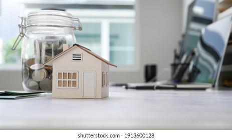 Home model and glass jars with coins putting on white table.
Planning savings money to buy a home or Property Investment concept.