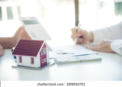 Home model. Hand signing on contract after the real estate agent explains the business contract, rent, purchase, mortgage, a loan, or home insurance to the buyer.