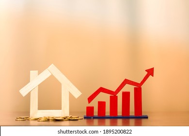 Home Model Put On The Gold Coin And Red Arrow And Bar Graph With Growing Value Put On The Desk In The Office, Buy Or Sell A House And Real Estate For Working Capital Concept.