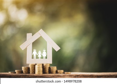 Home model put on a stack gold coin substantial and family with paper cut put inside put on the wood in the public park, Saving money for business investment or loan for real estate concept.