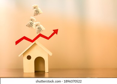 Home model and red arrow and bar graph with growing value with dropping the money bag on the top put on the desk in the office, Buy or sell a house and real estate for working capital concept.