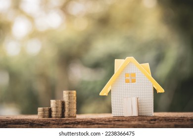 Home model and stack gold coin put on the wood in the in the public park, Saving money for real estate with buying a new home and loan for prepare in the future concept. - Shutterstock ID 2238366475