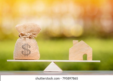 Home and money bag put on the scales with balance put on the wood in the public park, Saving for buy a new house or real estate and loan for plan business investment in the future concept. - Shutterstock ID 795897865