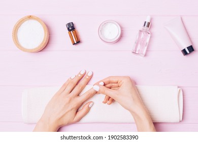 Home Nail Care, Female Hands Apply Nourishing Cuticle Cream On Pink Background, Top View.