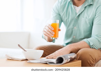 Home, News, Food, Drinks And People Concept - Close Up Of Man Reading Magazine And Drinking Juice Sitting On Couch At Home