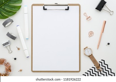 Home Office Desk With Clip Board Mockup, Glasses, Golden Stationery, Green Leaves And Color Markers For Drawing. Workspace Mock Up Arranged. Flat Lay, Top View