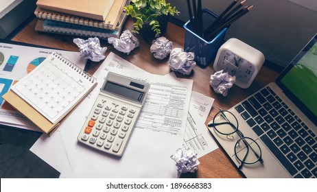 Home Office Desk Concept. Laptop, and calculator for accountant or bookkeeper plan annual budget report and tax. Computer, Crumpled paper, and pencil placed on wooden table.