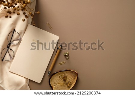 Home office desk table with weekly planner, pen, office stationery, glasses, beige cloth, dried flowers. Elegant, aesthetic feminine workspace.