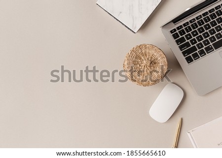 Home office desk workspace with laptop, straw casket on neutral background. Flat lay, top view blog, website, social media concept.