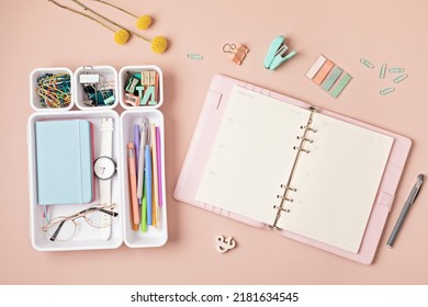 Home Office Desktop Over Pink Background. Modern Workspace With Notebook, Office Stationary In Plastic Organizers