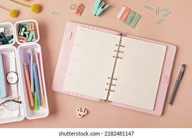 Home Office Desktop Over Pink Background. Modern Workspace With Notebook, Office Stationary In Plastic Organizers