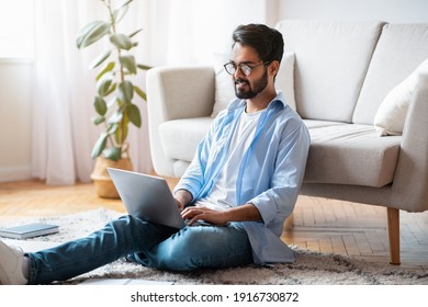 Home Office. Handsome Eastern Male Freelancer Working With Laptop In Living Room, Smiling Millennial Arab Guy Sitting On Floor With Computer Enjoying Remote Job Opportunities, Copy Space