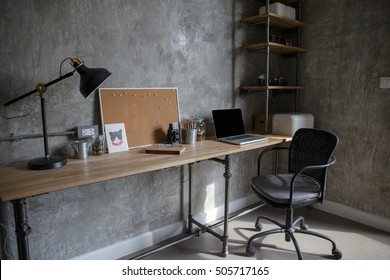 Home office interior in loft space with wooden table, office supplies, documents, notebook and laptop,