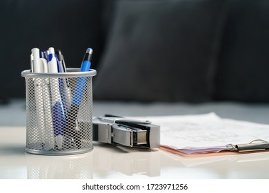 Home office stapler pencils and clipboard with documents and papers on the white table at home or office front view low angle empty lockdown