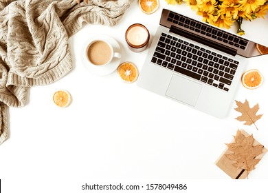 Home office table desk workspace with laptop decorated with yellow daisy flowers bouquet, coffee cup, orange slices, plaid. Flat lay, top view freelance business concept for social media, magazine.