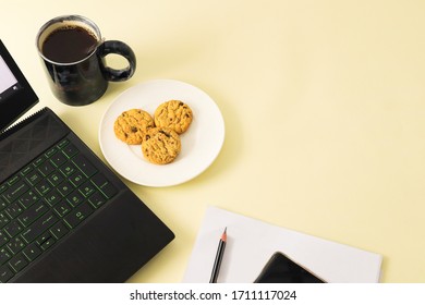 HOME OFFICE TABLE WITH NOTEBOOK COMPUTER AND ACCESSORY AND SOME DRINK ON TABLE AS WELL.